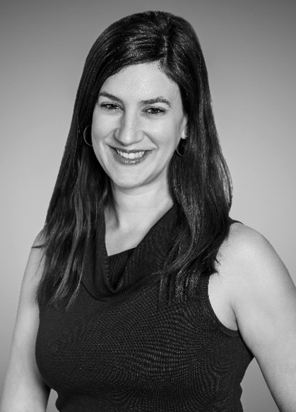 Black and white portrait of a smiling person with long hair, wearing a sleeveless top.