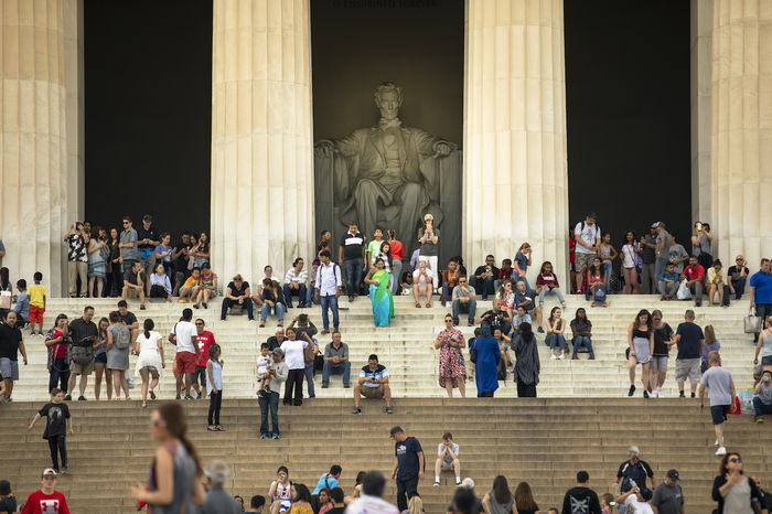 People gathered on the steps of the Lincoln Memorial, with the statue of Abraham Lincoln visible in the background.