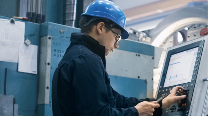 Man wearing hard hat operating a CNC Machine