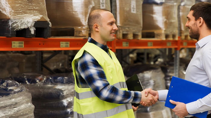 Warehouse worker shaking hands with a sales representative