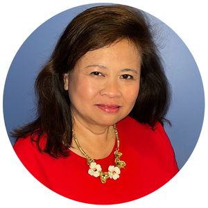 A woman with shoulder-length dark hair wearing a red top and floral necklace, set against a blue background.
