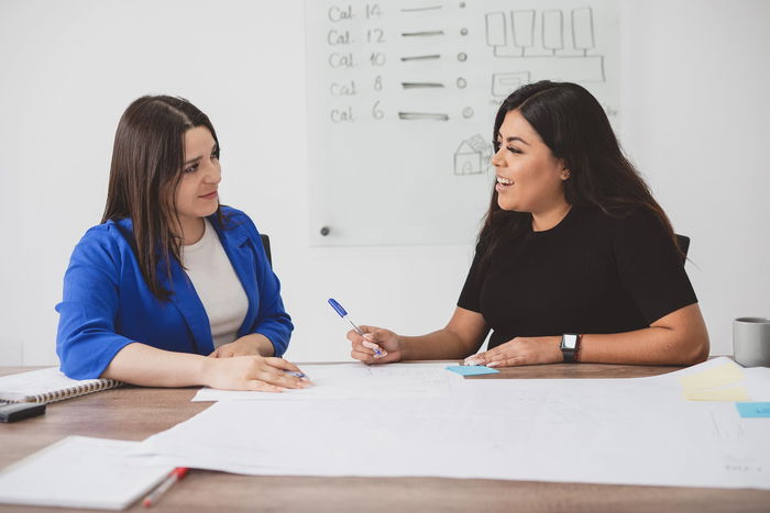 Two colleagues in a conference room talking.