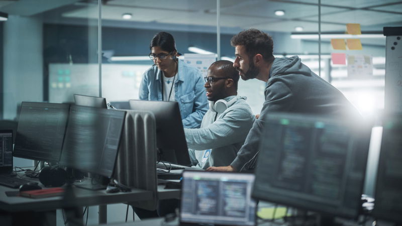 Diverse Group of Professionals Meeting in Modern Office: Brainstorming IT Programmers Use Computer Together, Talk Strategy, Discuss Planning. Software Engineers Develop Inspirational App Program