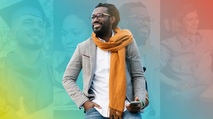 A man in a gray blazer and orange scarf stands smiling with a smartphone, against a colorful blurred background of various people.