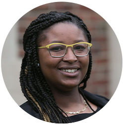 Person with braided hair and yellow glasses, smiling.