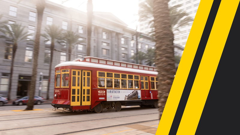 A red streetcar travels along a city street lined with palm trees and modern buildings, with a yellow and black design accent on the right side of the image.