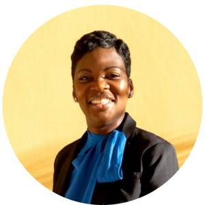 A person in a dark jacket and blue shirt smiles against a yellow background.