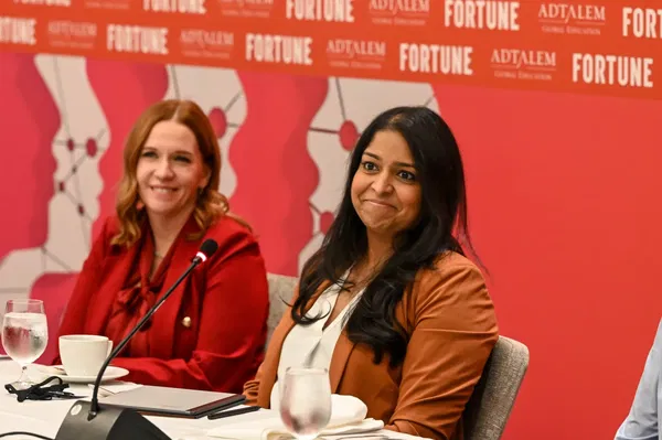 Two women sit at a panel table with microphones. The background displays logos for Adtalem and Fortune.