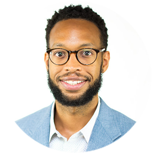 A person with glasses, a beard, and wearing a blue blazer over a white shirt, smiling at the camera.