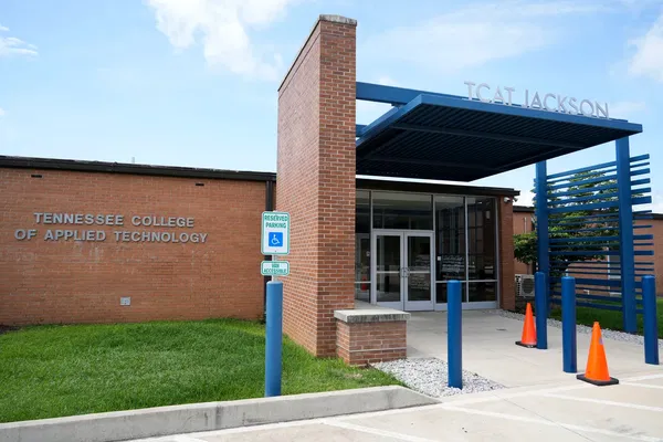 Exterior view of the Tennessee College of Applied Technology Jackson building, showing entrance, accessible parking sign, and orange traffic cones.
