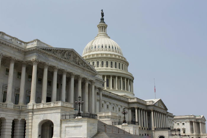 The United States Capitol building with its dome and columns, shown from an exterior angle on a clear day.
